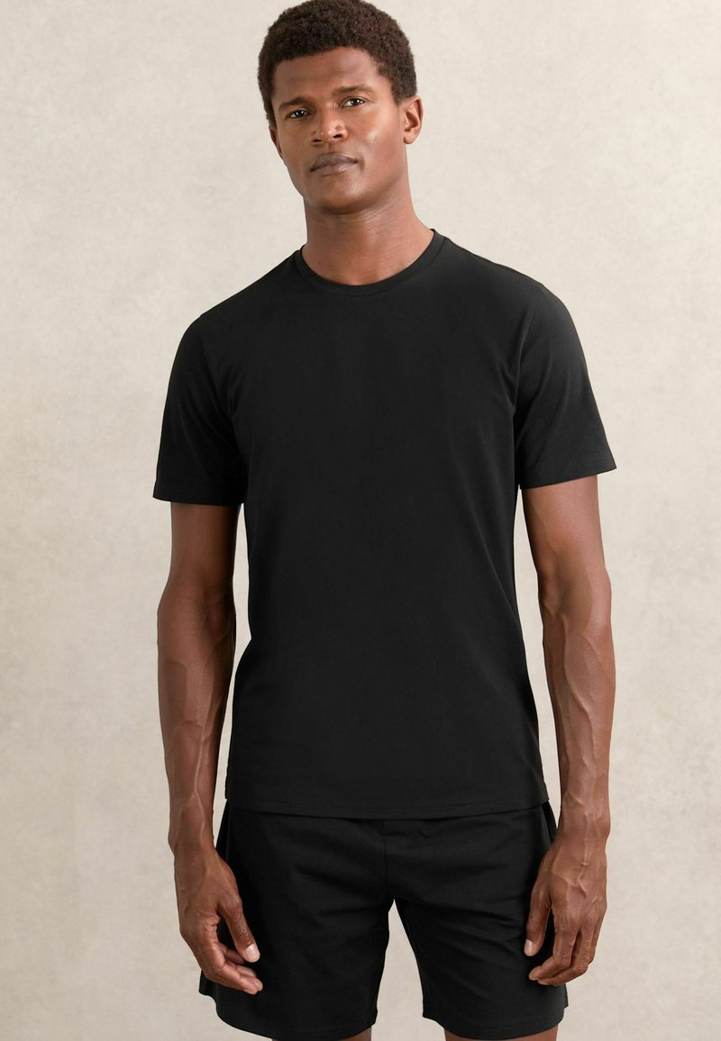 Tricou negru cu mânecă scurtă, fabricat dintr-un material moale, având un design clasic cu guler rotund și o textură simplă, netedă.