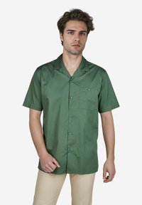Korte mouwen groene shirt gemaakt van gladde stof met een knoopsluiting aan de voorkant, een patchzak en een klassiek kraagontwerp.
