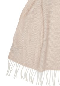 Coperta intrecciata in un morbido beige con un motivo a zigzag. Presenta frange bianche lungo i bordi, aggiungendo texture e dettaglio.