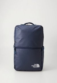 Jūras zila mugursoma no izturīga sintētiska materiāla ar priekšējo rāvējslēdzēja kabatu, logotipa akcentu un strukturētu taisnstūrveida formu.