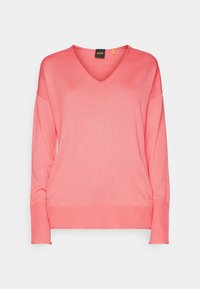 Svetr s výstřihem do V v jemně růžové barvě, vyrobený z pletené tkaniny, s kleslými ramenními švy a žebrovanými manžetami. Minimalistický design, bez vzorů.