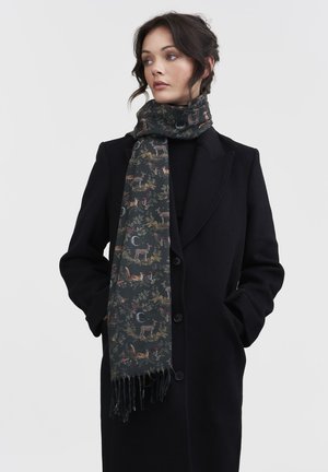 Sciarpa scura con motivo di animali e foglie, realizzata in morbido tessuto, con bordi frangiati, indossata sopra un cappotto nero.