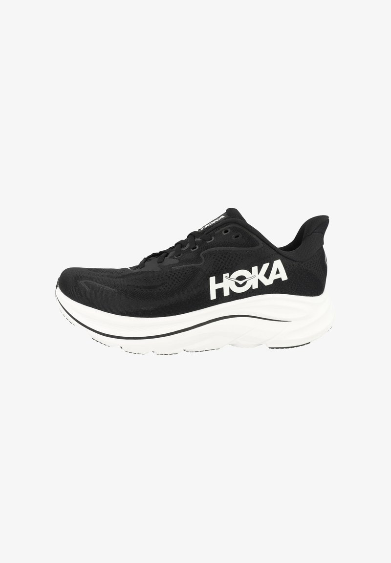 Musta juoksukengä, jossa on verkkokangas yläosa, valkoinen HOKA-logo, paksu valkoinen välipohja, teksturoitu yksityiskohta, ja musta ulkopohja, jossa on uria pitoa varten.