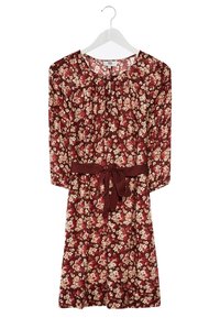 Robe rouge à fleurs longueur genou avec manches 3/4 et ceinture assortie en tissu nouée à la taille, suspendue sur un cintre blanc.