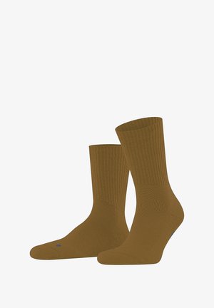 Chaussettes brunes côtelées présentées avec un ajustement confortable, arborant un logo discret sur le bout. Convient pour un usage décontracté ou quotidien.
