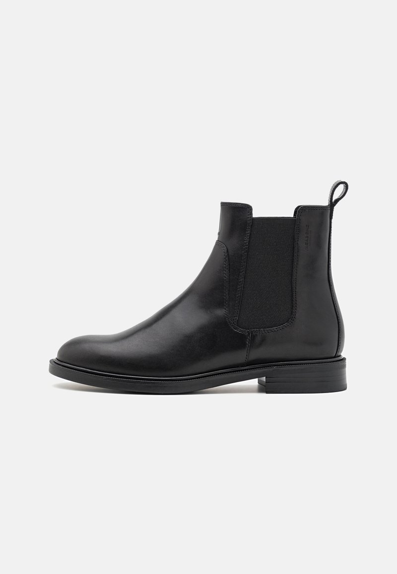 Stivale Chelsea in pelle nera con pannelli laterali in elastico, tacco basso impilato e linguetta, su sfondo bianco, mostrato dal lato sinistro.