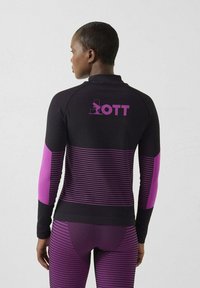Top deportivo negro con rayas horizontales y detalles morados. Cuenta con un cuello alto y la palabra "OTT" impresa en la espalda.