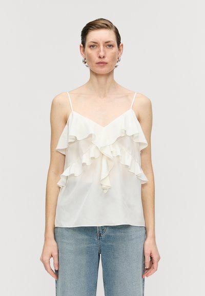 Blouse blanche sans manches avec des volants superposés sur le devant, faite en tissu léger. Présente des bretelles spaghetti fines et un décolleté en V.