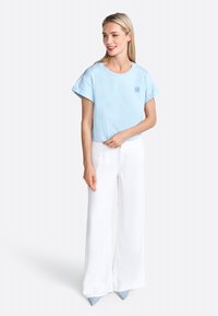 Haut bleu clair à manches courtes avec un col rond ; associé à un pantalon large blanc et des chaussures pointues bleu clair. Design simple et décontracté.