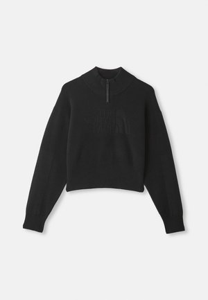 Melna piegriezta džemperis ar augstu apkakli, pusei rāvējslēdzis, ribota aproce un apakšmala. Priekšpusē ir smalka reljefa logo.