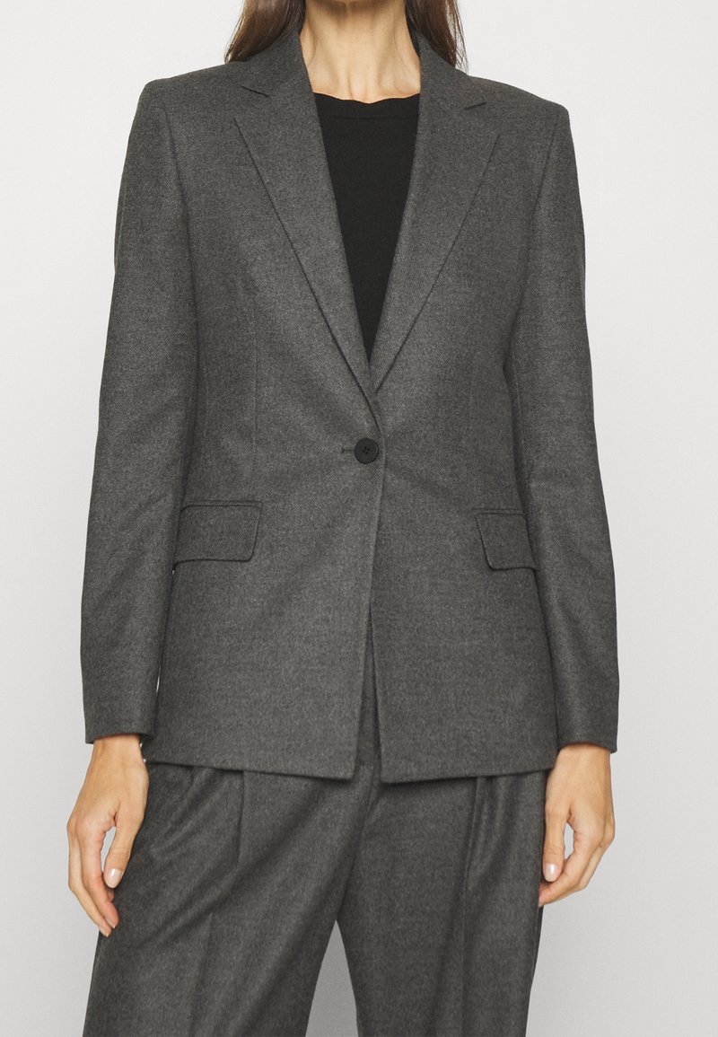 Szary, dopasowany żakiet z jednym guzikiem, klapami typu notch oraz dwiema kieszeniami z przodu. Miękka tekstura, zdefiniowany kształt i minimalistyczny design.