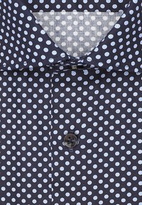 Granatowa koszula z zapięciem na guziki, ozdobiona wzorem małych niebieskich i białych kropek. Posiada kołnierz i drobną teksturę.
