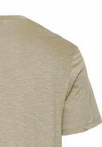 Kortærmet t-shirt i lys beige, lavet af blødt stof med en subtil tekstur. Har rund halsudskæring og en ren afslutning ved ærmerne.