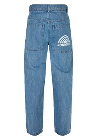 Vaaleansiniset farkut rentona istuvana, joissa on takataskut ja "SOUTHPOL" -logo sateenkaaren suunnittelulla oikeassa taskussa.