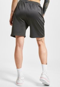 Grå treningsshorts med elastisk linning, med en glatt tekstur og en løs passform, sammen med hvite treningssko og sokker.