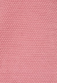 Texturerad rosa stickad tyg med ett konsekvent mönster av små upphöjda bollar, vilket ger en mjuk och mysig känsla.