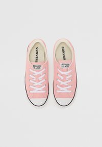 Rosa Canvas-Sneaker mit weißen Schnürsenkeln, schwarzer Gummi-Zehenkappe und kontrastierender schwarzer Sohle. Hat ein Logo-Patch auf der Zunge.
