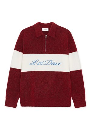 Rød og hvit farger blokkgenser med glidelåsslukking, med "Les Deux" brodert i blått. Laget av mykt, teksturert stoff.