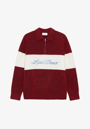 Rød og hvit farger blokkgenser med glidelåsslukking, med "Les Deux" brodert i blått. Laget av mykt, teksturert stoff.