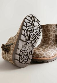 Stivali alla caviglia in suede con stampa leopardata e suola in gomma, dotati di una cerniera decorativa e battistrada con motivo floreale. Colore: beige e marrone.