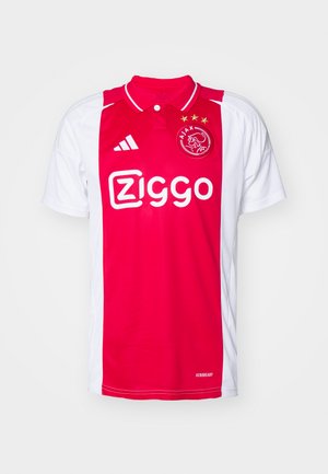 Rode en witte voetbalshirt met een kraag, voorzien van een zigzagontwerp en het logo "Ziggo" in het wit prominent weergegeven. Drie gouden sterren boven het logo.