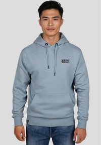 Felpa leggera di colore azzurro con tasca a marsupio e cappuccio con cordino. Presenta un testo logo nero sul petto. Realizzata in un morbido tessuto strutturato.