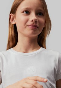 Witte katoenen T-shirt met ronde hals en korte mouwen, met een geborduurd "cK" logo op de borst. Vaste textuur.