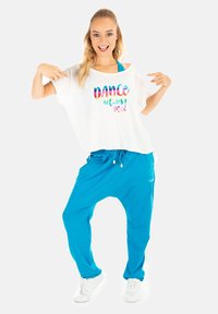 Losse witte T-shirt met regenboogtekst "DANCE defines me!" gecombineerd met felblauwe joggers, met een elastische tailleband en koordjes.