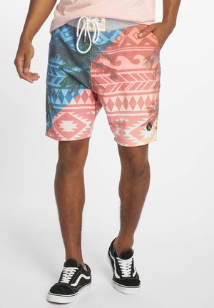 Costumi da bagno multicolori con un motivo geometrico in rosa, blu e bianco; include dettagli con palme e una vita con coulisse.