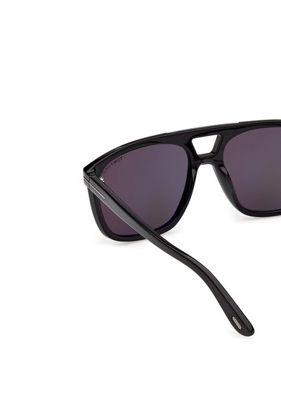 Lunettes de soleil rectangulaires oversize noires avec des verres teintés foncés et un détail découpé sur le pont, montrant une branche de lunettes pliée.