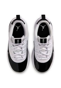 Des chaussures de sport blanches et noires avec un bout en vernis noir lisse et brillant, une tige en maille blanche texturée et un logo noir sur la semelle intérieure.