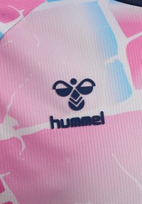 Ciemnoniebieskie logo pszczoły Hummel oraz tekst na różowym, białym i jasnoniebieskim wzorzystym, teksturowanym tle materiałowym.