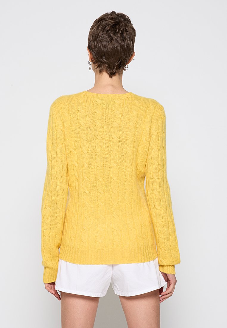 Żółty sweter dzianinowy z wzorem w warkocze, długie rękawy, okrągły dekolt oraz ściągacze na mankietach i u dołu. Miękka tekstura, odpowiedni do noszenia w warstwach.