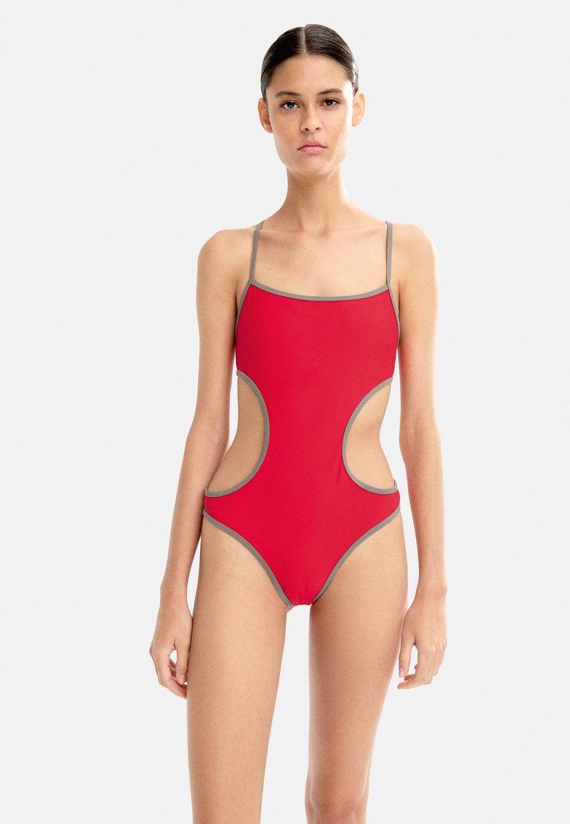 Czerwony jednoczęściowy strój kąpielowy z szarym wykończeniem, z wyciętymi bokami i cienkimi ramiączkami. Gładki, elastyczny materiał z dopasowanym krojem.
