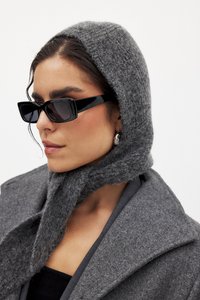 Hallide villasegu müts ja mantel, koos stiilsete mustade ristkülikukujuliste prillidega. Omab tekstureeritud kangast ja kohandatud siluetti.