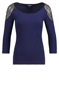 Dunkelblaues Langarmshirt aus weichem Stoff, mit schwarzen Spitzenakzenten an den Schultern und einem runden Ausschnitt. Schlanker Schnitt.