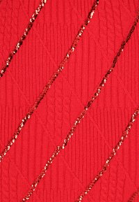 Roter Strickstoff mit einem strukturierten Diamantmuster, akzentuiert durch diagonale Linien aus roten Pailletten für zusätzlichen Glanz und Detail.