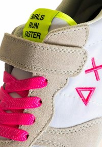 Sneaker grigio e bianco con lacci e accenti rosa. Presenta la scritta "LE RAGAZZE CORRONO PIÙ VELOCE" su un'etichetta gialla brillante. Include materiali in suede testurizzato e nylon.