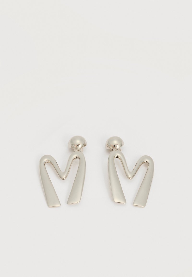 Ζευγάρι ασημί μεταλλικά σκουλαρίκια σε σχήμα γωνιώδους γράμματος Μ με στρογγυλεμένους ακροδέκτες σε λευκό φόντο.
