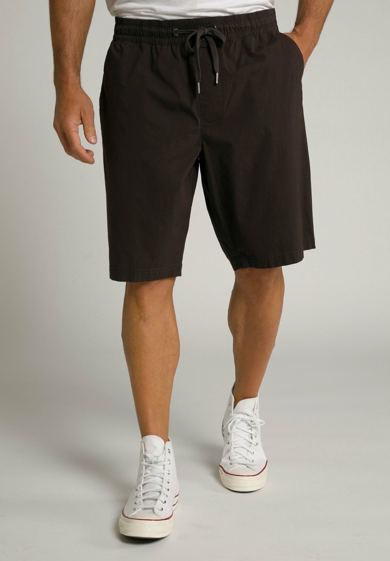 Brune cargo shorts med elastisk talje og snoretræk, parret med hvide højtoppede sneakers. Glat tekstur, afslappet pasform.