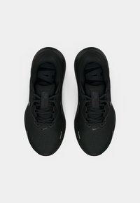 Une paire de chaussures de course noires Nike avec lacets, vue de dessus sur un fond blanc.