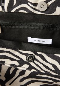 Interno in tessuto a stampa zebra con una tasca nera con zip. Presenta un bottone a pressione argentato e un'etichetta bianca con il testo "TERRANOVA".