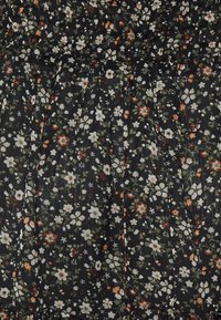 Gros plan d'un tissu noir avec un motif à petites fleurs blanches, orange et vertes dispersées densément sur la surface.