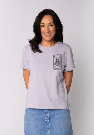 Lila Baumwoll-T-Shirt mit Rundhalsausschnitt, das auf der linken Brust einen schwarzen Grafikdruck in Form eines Tarotkarten-Designs aufweist. Glatte Textur.