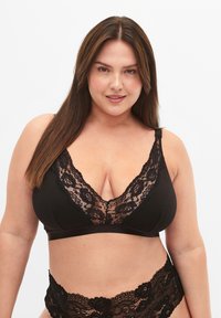 Black bralette with lace trim, featuring a deep V-neck design and adjustable straps. Soft fabric provides comfort with a seamless finish.