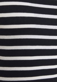 Nahaufnahme von schwarz-weiß gestreiftem Strickstoff mit abwechselnd breiten und schmalen Streifen.