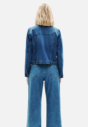 Chaqueta de mezclilla con un lavado azul oscuro, cierres de botón y bolsillos de parche, combinada con pantalones de mezclilla de pierna ancha en azul oscuro que cuentan con bolsillos traseros.