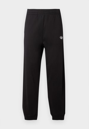 Black sweatpants feature an elastic waistband, tapered legs, and a small white logo on the left side. Fabric has a smooth texture.