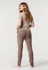 Top curto de mangas curtas com riscas castanhas, combinado com calças ajustadas em tom taupe, apresentando uma textura suave e uma cintura elástica. Modelo posando de costas.