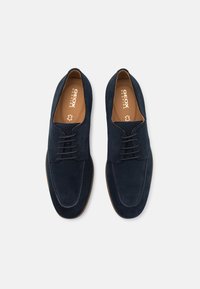 Pantofi din suede albastru marin, cu șnur, cu un finisaj neted, vârf rotund și talpă contrastantă de nuanță bej. Logo-ul este vizibil pe interiorul tălpii.
